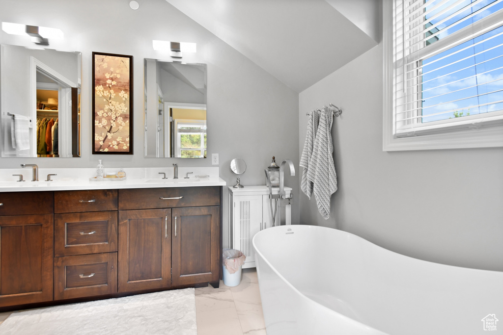 Bathroom with vanity, lofted ceiling, plenty of natural light, and a bath