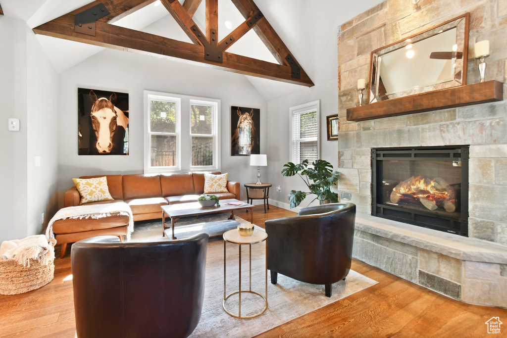 Living room with a fireplace, high vaulted ceiling, hardwood / wood-style floors, and beam ceiling