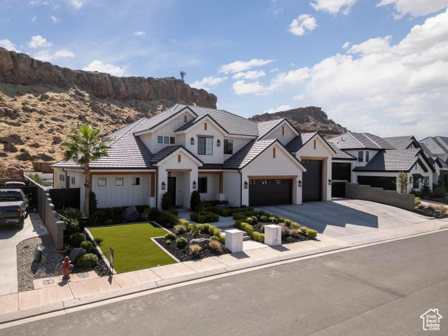 View of front facade with a garage, a mountain view, and a front lawn