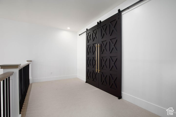 Corridor with a barn door and light colored carpet