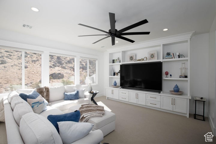 Living room featuring built in features, light carpet, and ceiling fan