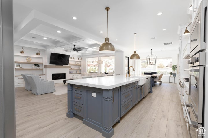 Kitchen featuring light hardwood / wood-style flooring, hanging light fixtures, sink, and white cabinets