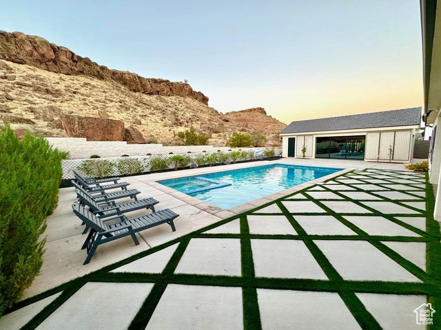 Pool at dusk featuring a patio and a mountain view