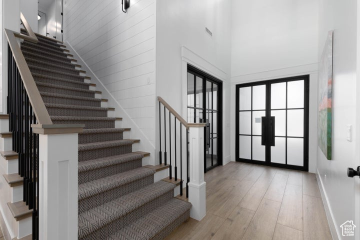 Entryway featuring french doors, a high ceiling, and light hardwood / wood-style flooring