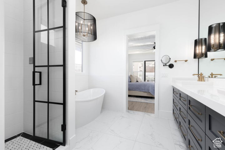 Bathroom with vanity, shower with separate bathtub, and ceiling fan with notable chandelier