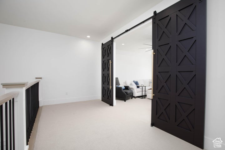 Corridor featuring light colored carpet and a barn door