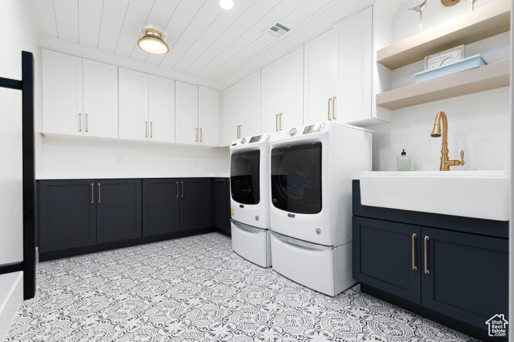 Clothes washing area with wood ceiling, washer and dryer, cabinets, and sink