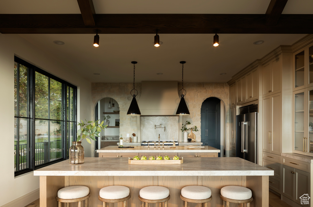 Kitchen with a spacious island, beamed ceiling, stainless steel built in fridge, and a breakfast bar area