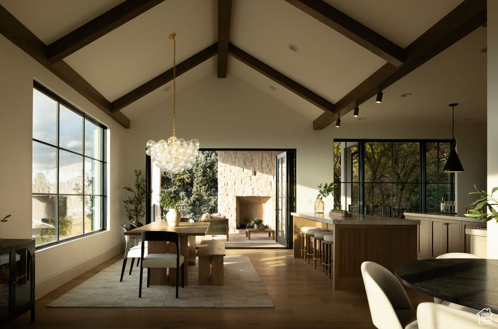 Dining area featuring high vaulted ceiling, light hardwood / wood-style floors, a chandelier, and beam ceiling