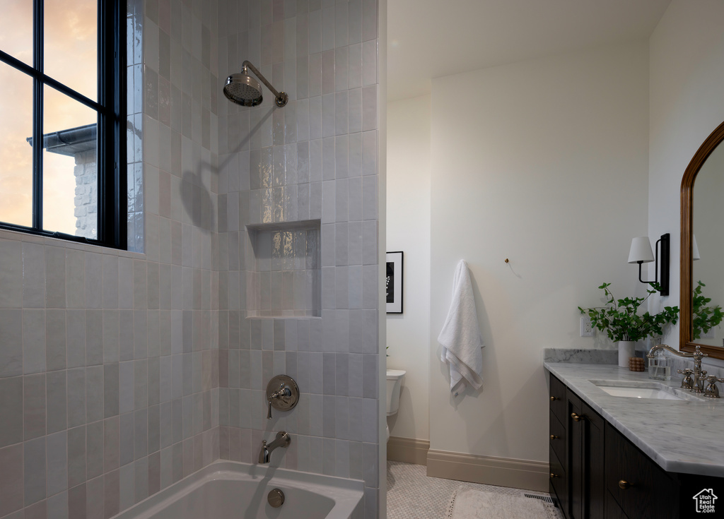 Full bathroom featuring tile patterned flooring, vanity, tiled shower / bath combo, and toilet