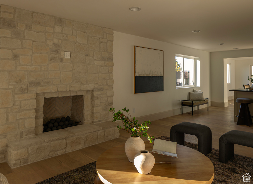 Living room with a stone fireplace and hardwood / wood-style floors