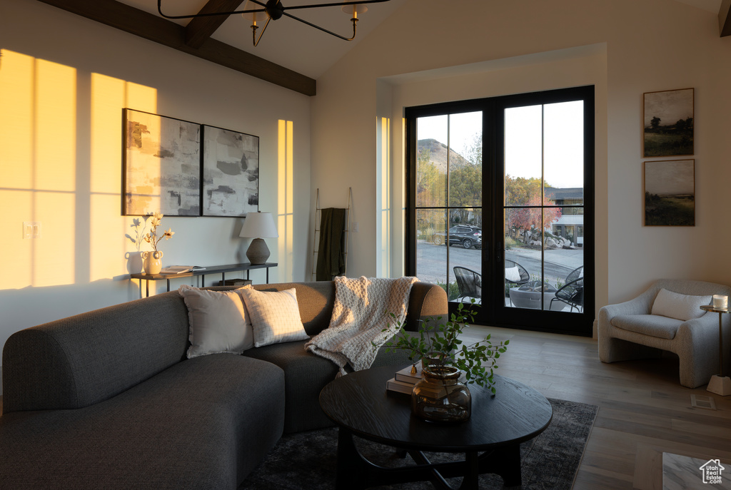 Living room with lofted ceiling with beams, a chandelier, and wood-type flooring