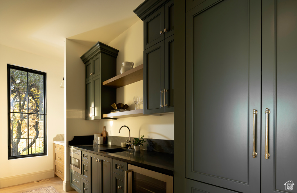 Kitchen with light hardwood / wood-style floors, beverage cooler, and sink