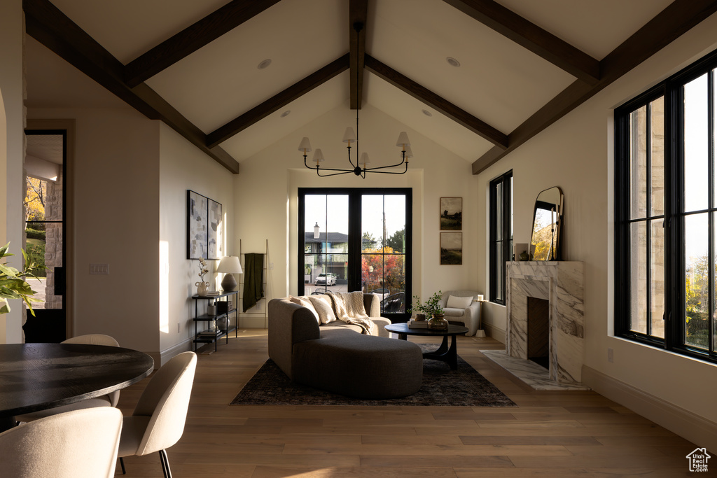 Living room with wood-type flooring, a chandelier, high vaulted ceiling, beamed ceiling, and a fireplace