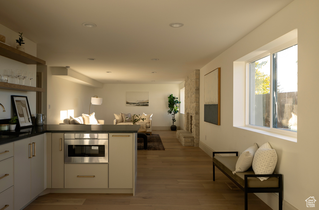 Kitchen featuring light wood-type flooring, white cabinetry, oven, and kitchen peninsula