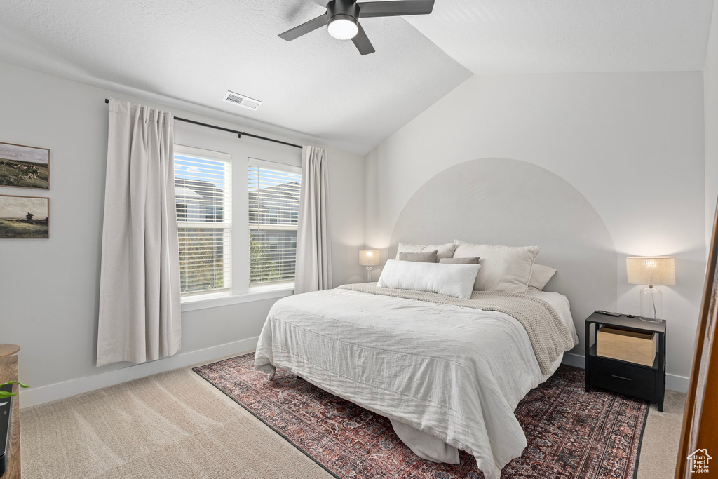 Carpeted bedroom featuring ceiling fan and vaulted ceiling