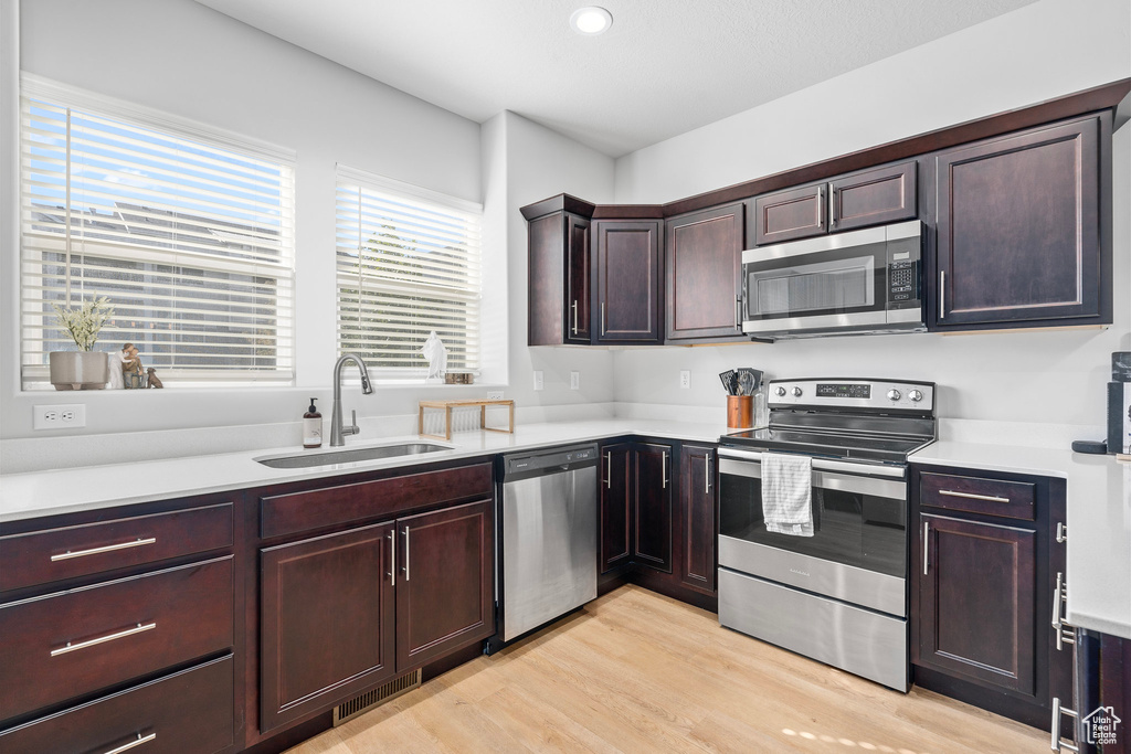 Kitchen featuring appliances with stainless steel finishes, light wood-type flooring, and sink