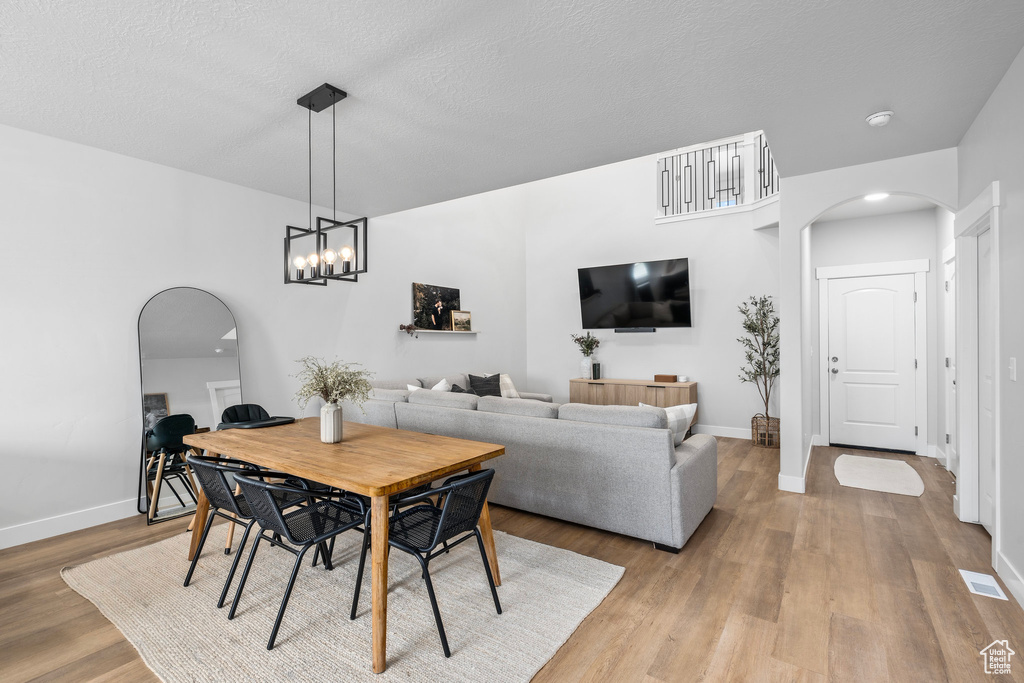 Dining space with a notable chandelier, light hardwood / wood-style floors, and a textured ceiling