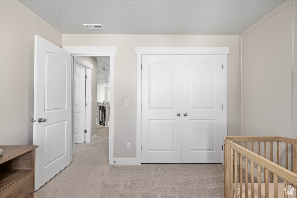 Carpeted bedroom featuring a crib and a closet