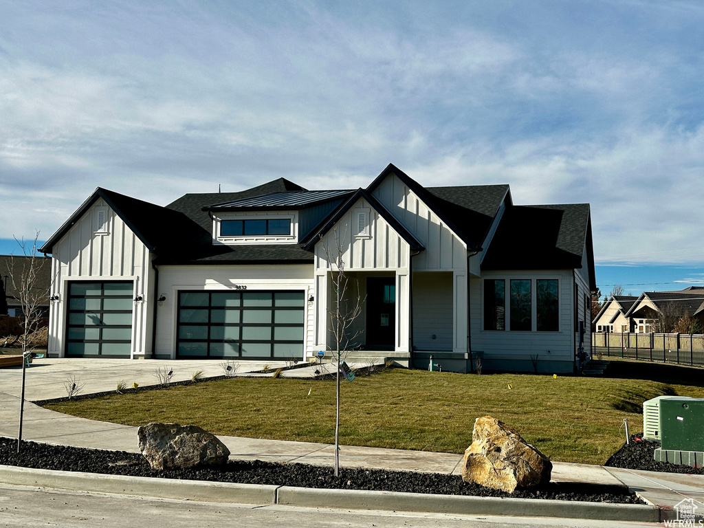 Modern inspired farmhouse with a garage and a front lawn