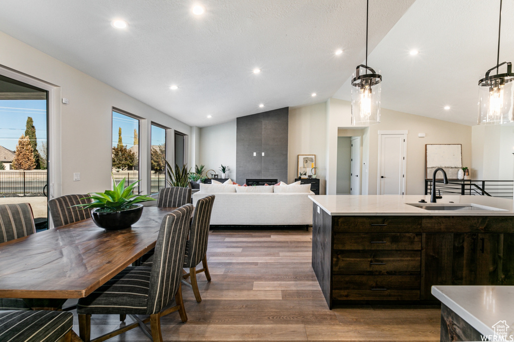 Kitchen featuring sink, dark brown cabinets, vaulted ceiling, pendant lighting, and hardwood / wood-style flooring