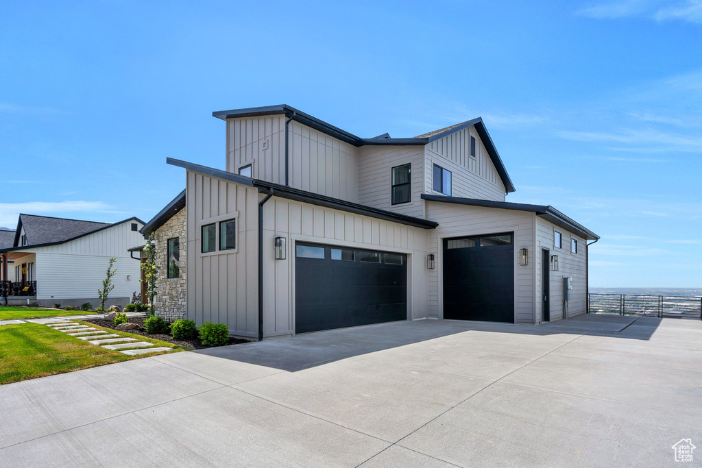 View of home\'s exterior with board and batten siding, concrete driveway, and a garage