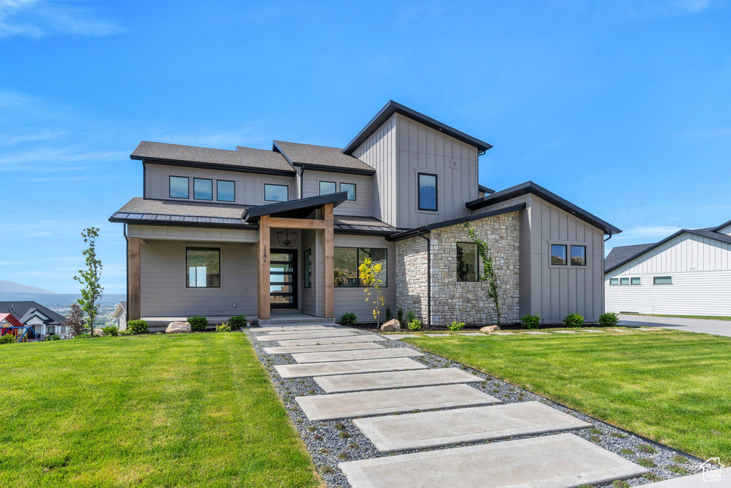Modern home with board and batten siding, a front yard, a standing seam roof, and a shingled roof