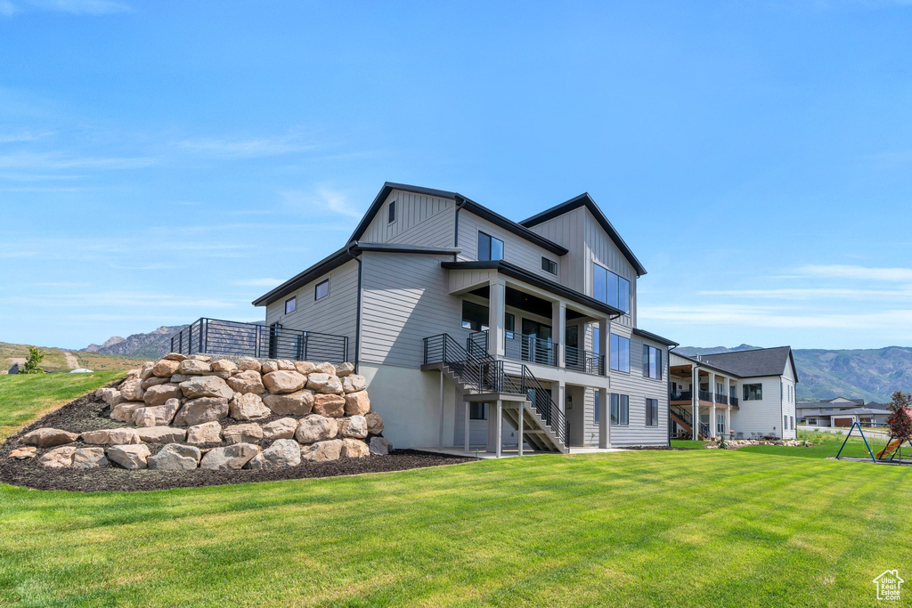 Back of property with a yard, stairs, and board and batten siding