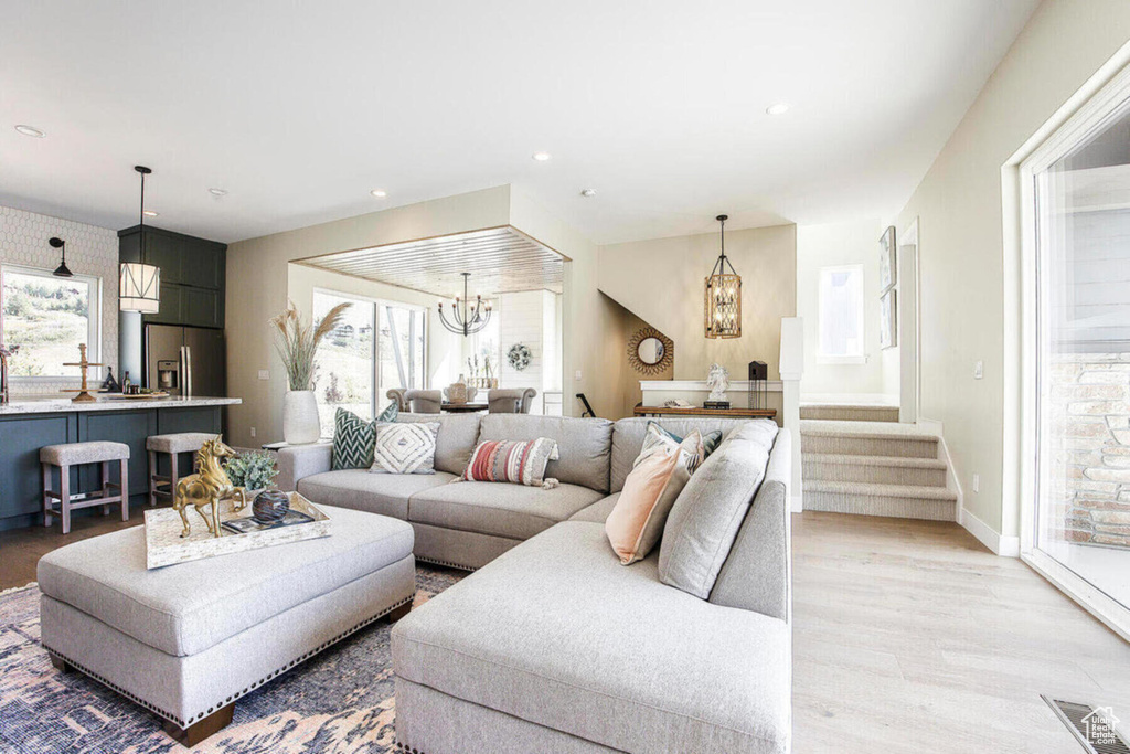 Living room with a wealth of natural light, an inviting chandelier, and light hardwood / wood-style floors