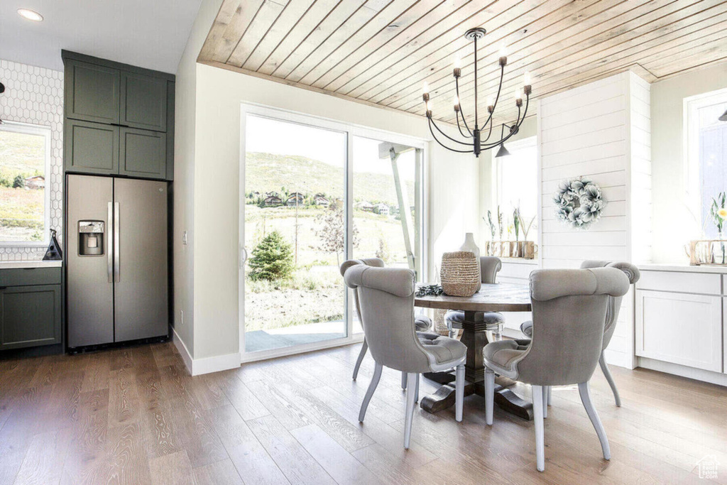 Dining area with a healthy amount of sunlight, a chandelier, wooden ceiling, and light hardwood / wood-style floors