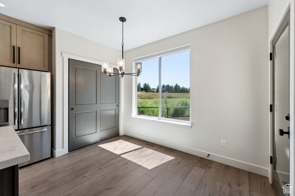 Unfurnished dining area with light hardwood / wood-style flooring and a chandelier