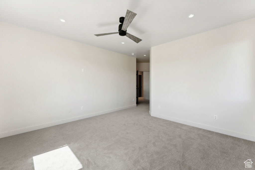 Spare room featuring light carpet and ceiling fan