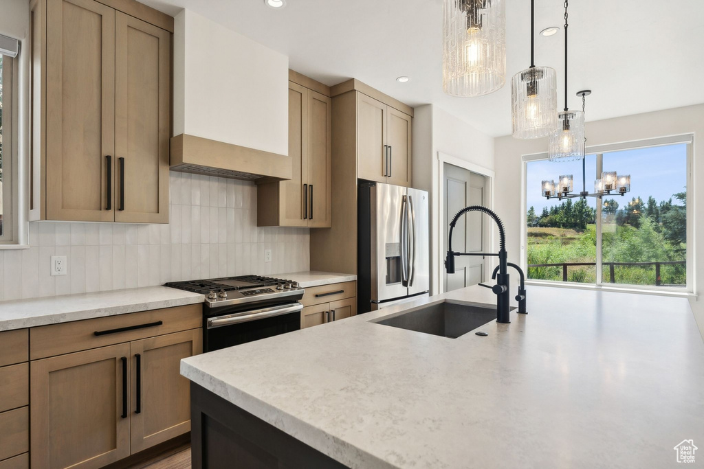 Kitchen with sink, a notable chandelier, appliances with stainless steel finishes, decorative light fixtures, and backsplash