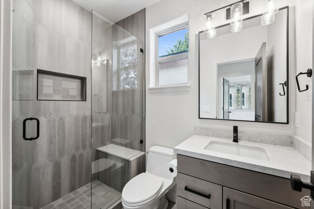 Bathroom featuring vanity, toilet, and an enclosed shower