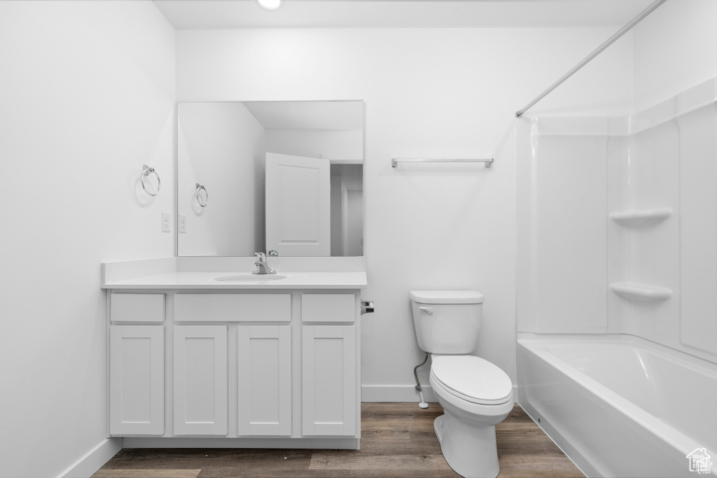 Full bathroom with hardwood / wood-style flooring, vanity, toilet, and  shower combination