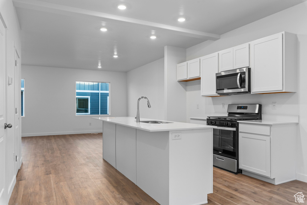 Kitchen featuring a kitchen island with sink, light hardwood / wood-style flooring, sink, stainless steel appliances, and white cabinetry