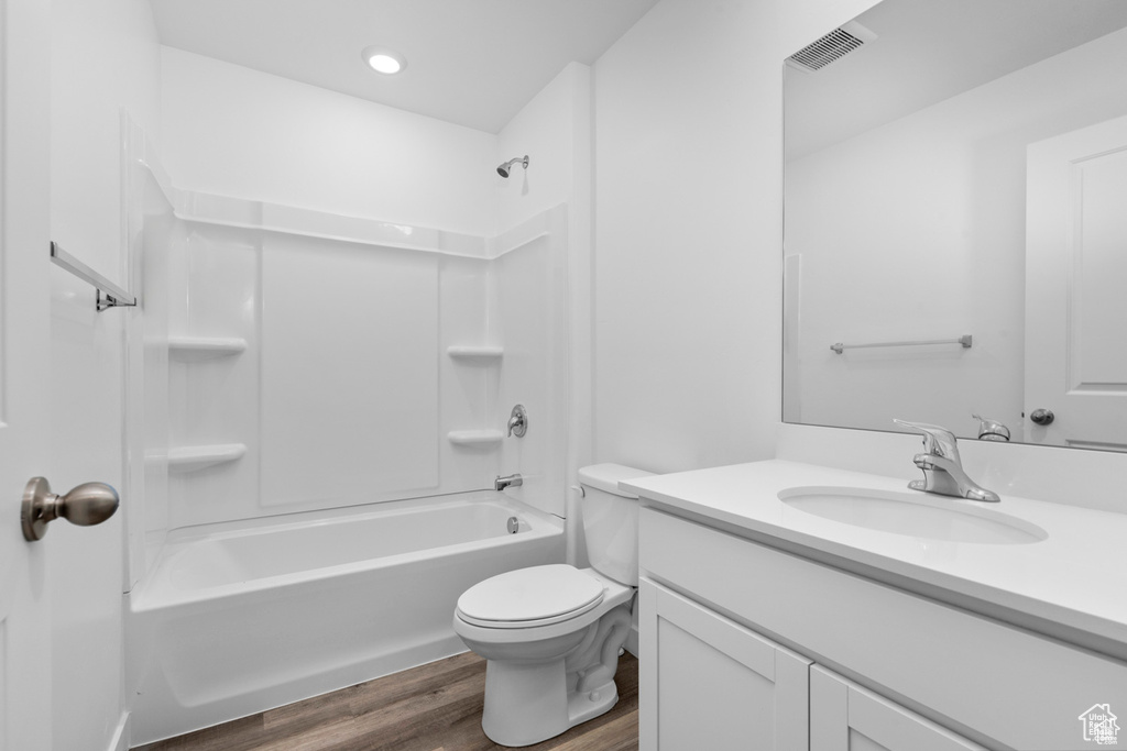 Full bathroom featuring wood-type flooring,  shower combination, vanity, and toilet