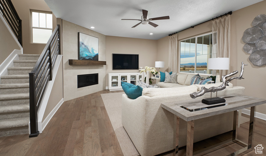 Living room with a fireplace, ceiling fan, and wood-type flooring