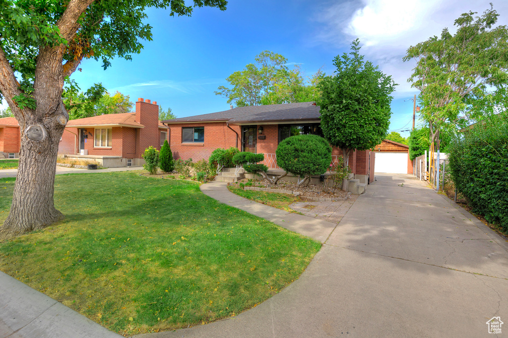 Ranch-style house featuring a front yard, a garage, and an outbuilding