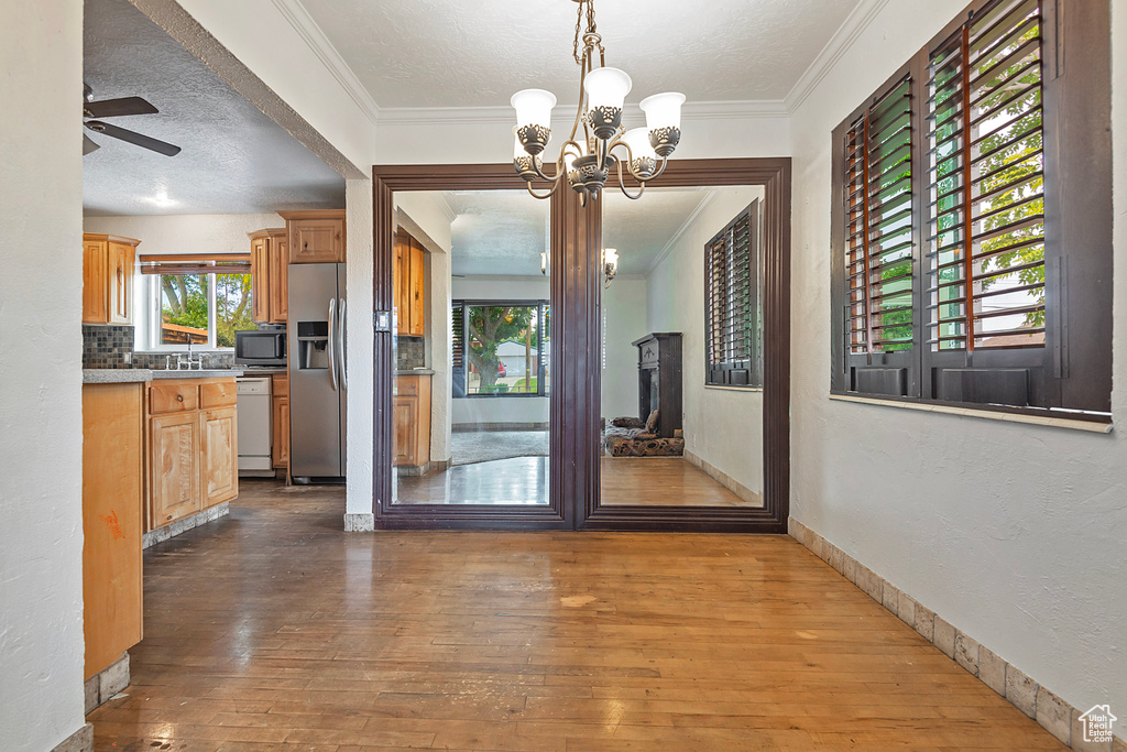 Unfurnished dining area with wood-type flooring, crown molding, and a wealth of natural light