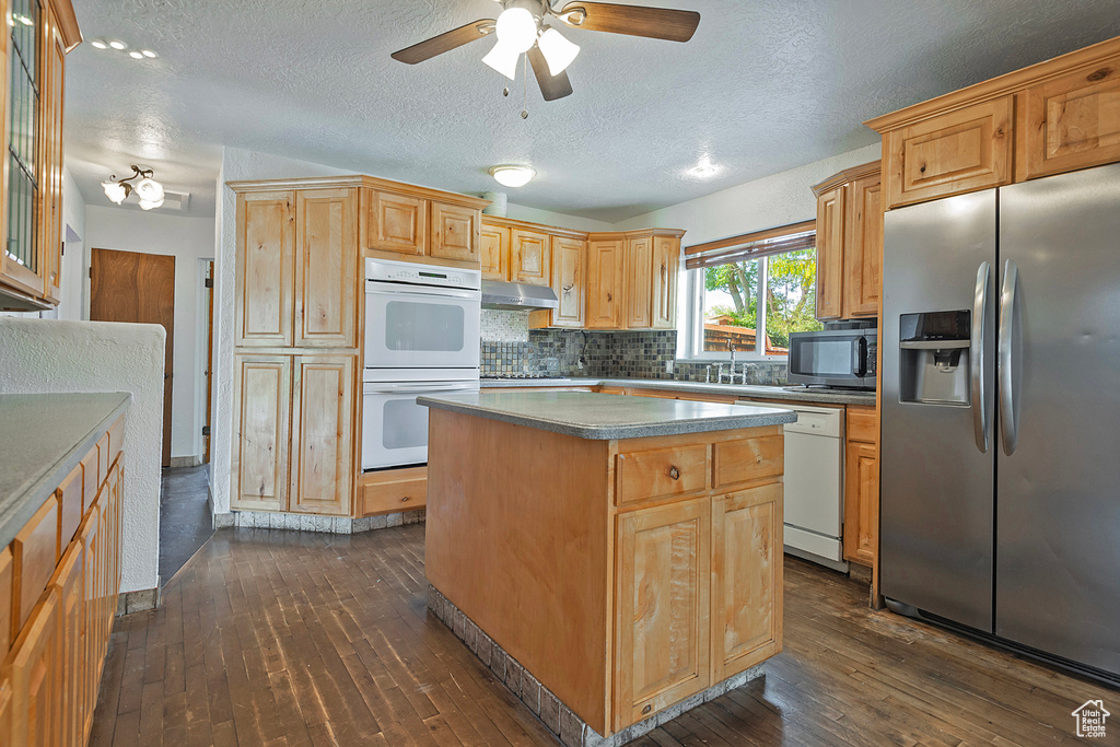 Kitchen featuring ceiling fan, a center island, dark wood-type flooring, appliances with stainless steel finishes, and a textured ceiling