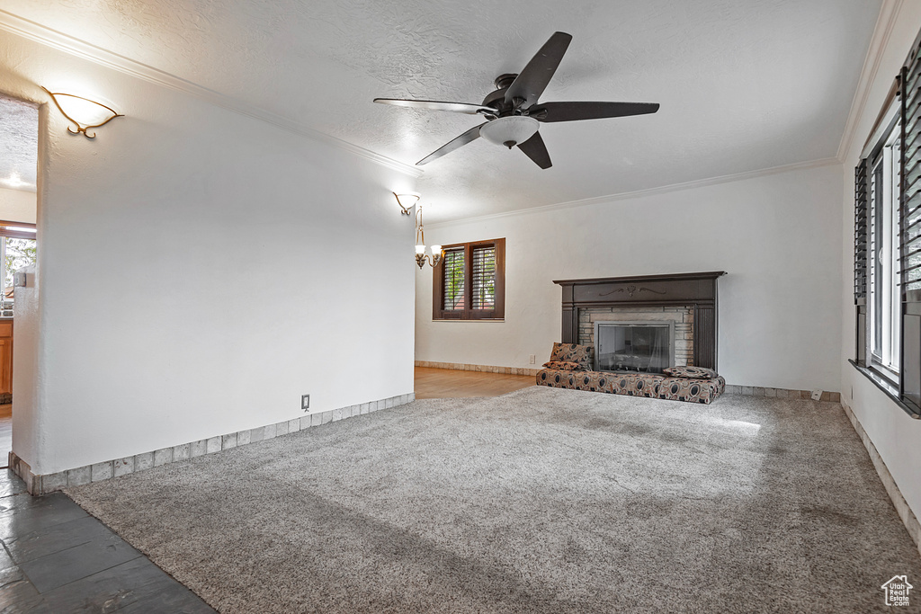 Unfurnished living room with a brick fireplace, crown molding, a wealth of natural light, and a textured ceiling