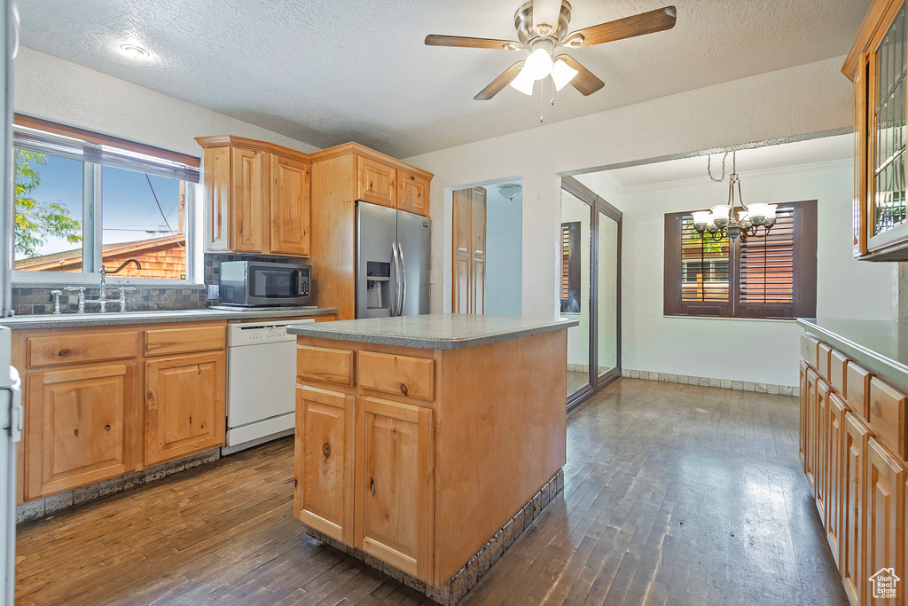 Kitchen featuring backsplash, sink, dark hardwood / wood-style floors, appliances with stainless steel finishes, and a center island