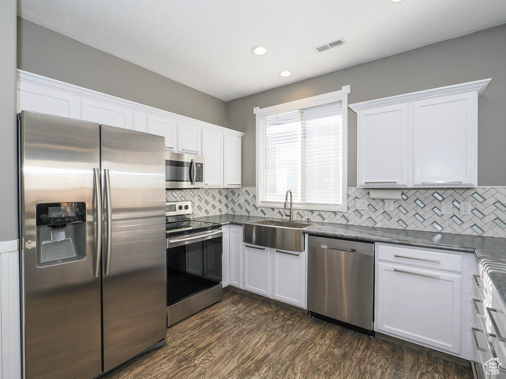 Kitchen with white cabinets, stainless steel appliances, sink, and dark hardwood / wood-style flooring