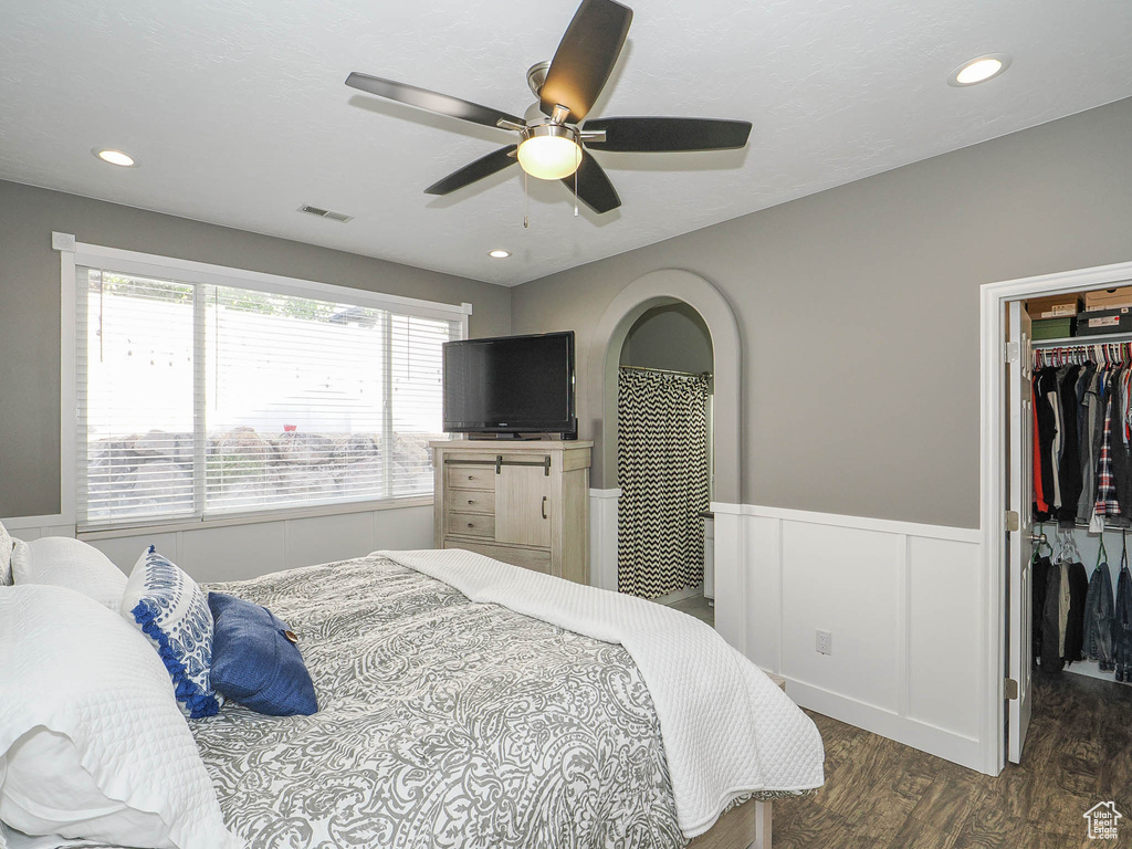 Bedroom featuring ceiling fan, a closet, dark wood-type flooring, and a walk in closet