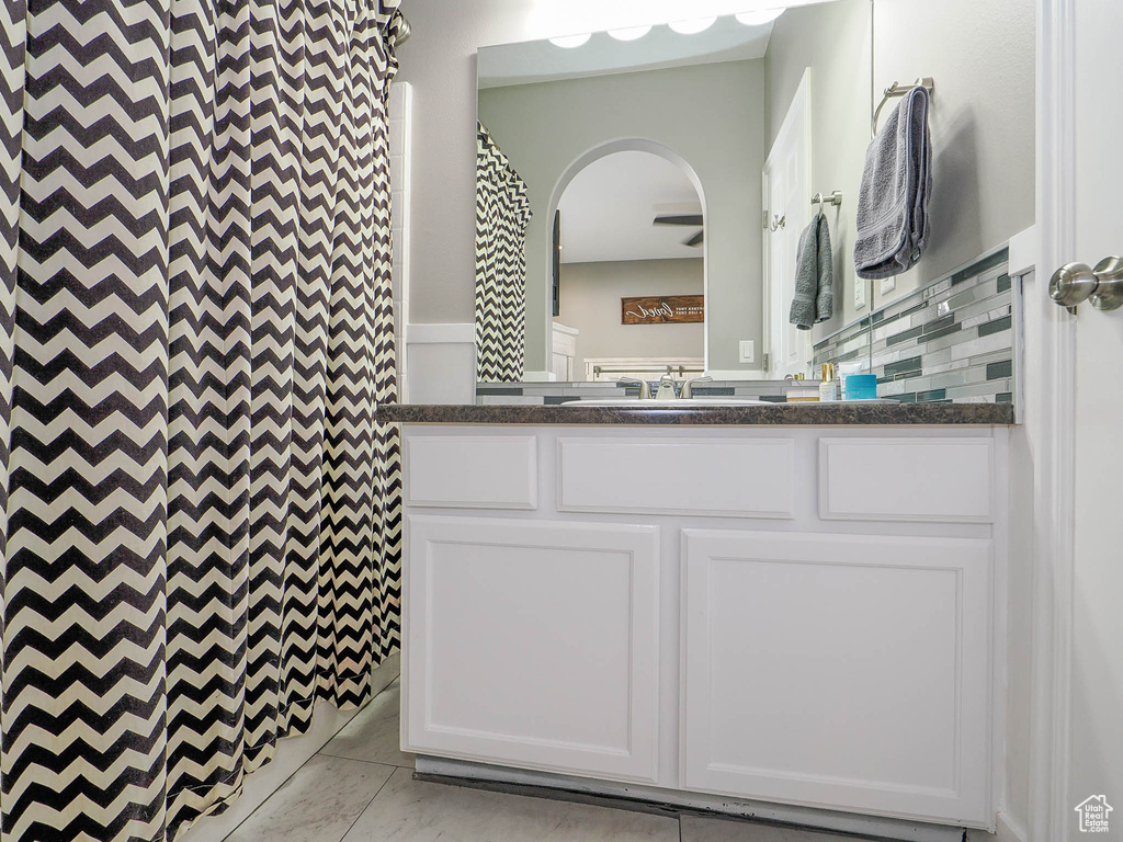 Bathroom with tile patterned floors, decorative backsplash, walk in shower, and vanity