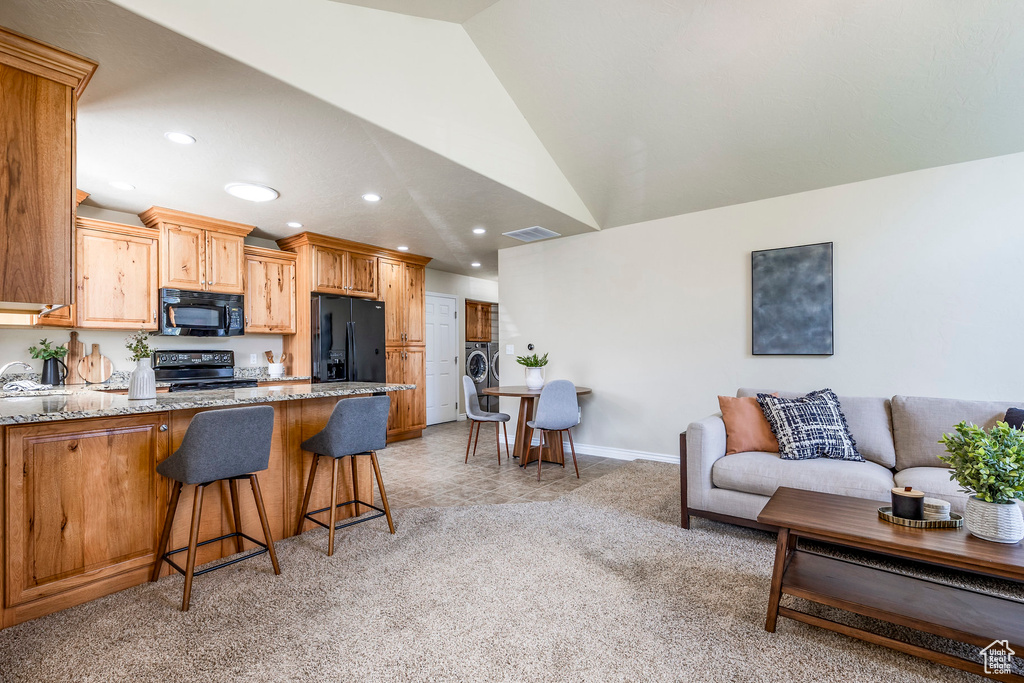 Kitchen featuring black appliances, light carpet, sink, a kitchen breakfast bar, and lofted ceiling