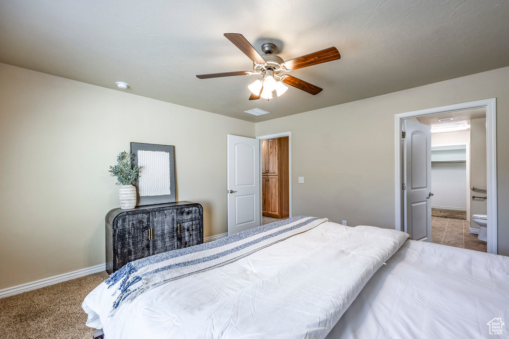 Carpeted bedroom with a closet, a walk in closet, ceiling fan, and ensuite bath