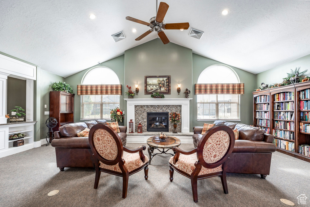 Living room with a wealth of natural light, lofted ceiling, ceiling fan, and carpet floors