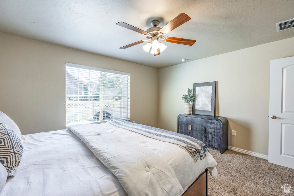 Carpeted bedroom with a textured ceiling and ceiling fan